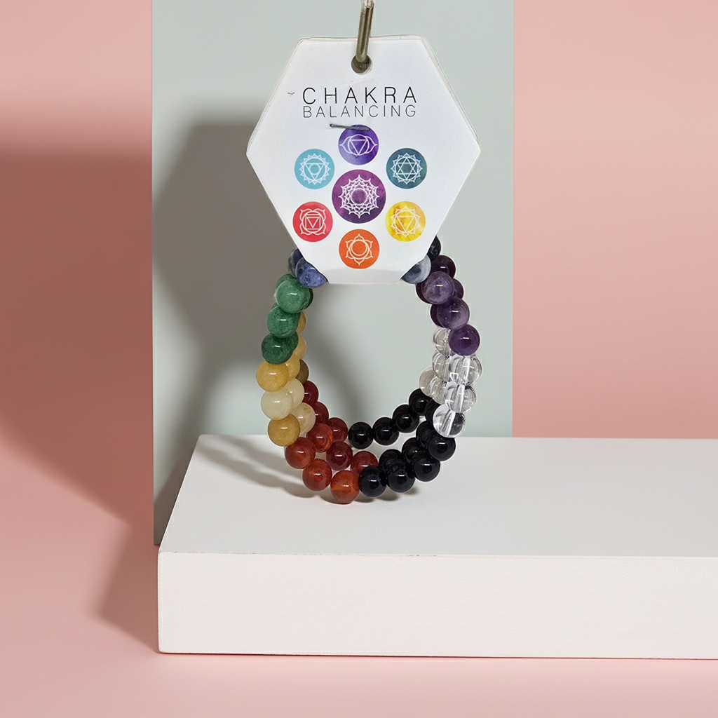 Set of chakra beaded bracelets on a white stand with a 'Chakra Balancing' card in the background.