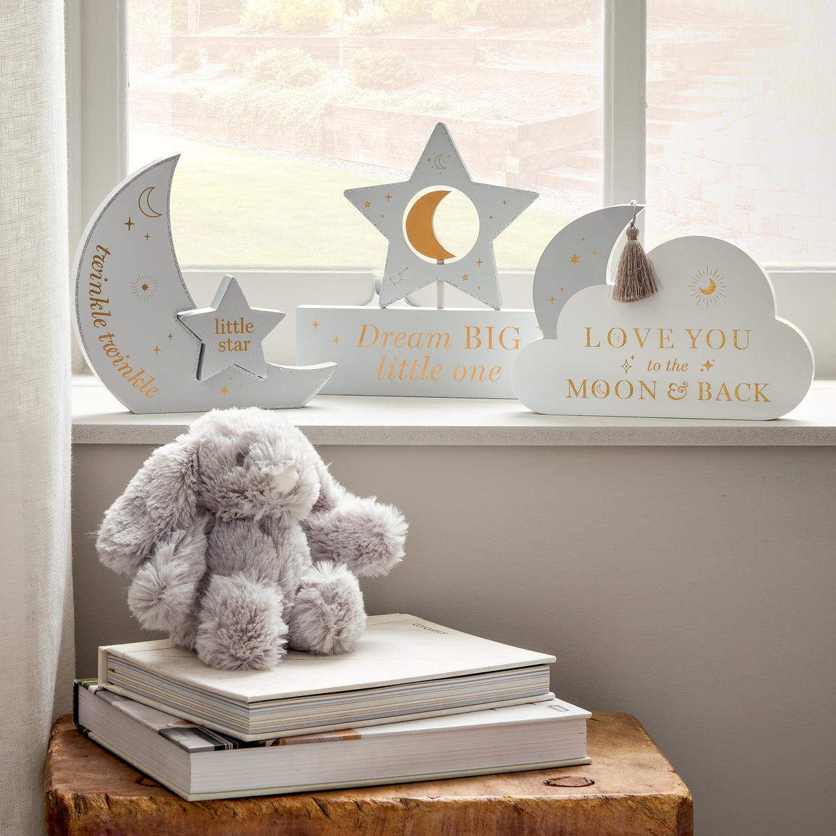 Decorative items including a plush toy, books, and wall hangings with motivational phrases in a softly lit room all available separately