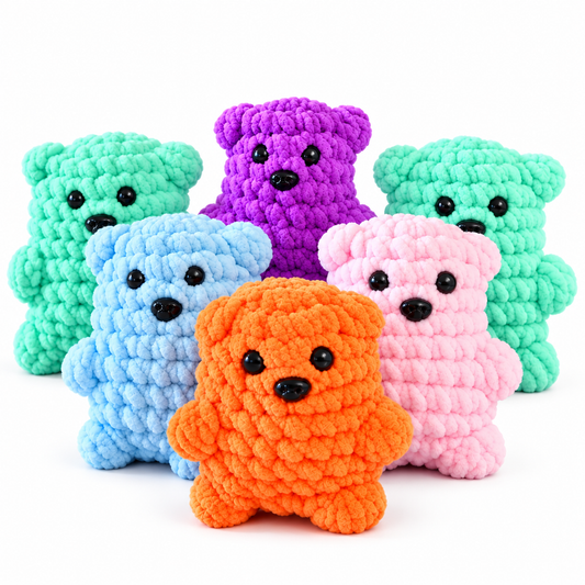 Six crocheted teddy bear toys in assorted colors, including mint green, purple, light blue, pink, and orange, arranged together on a plain white background.