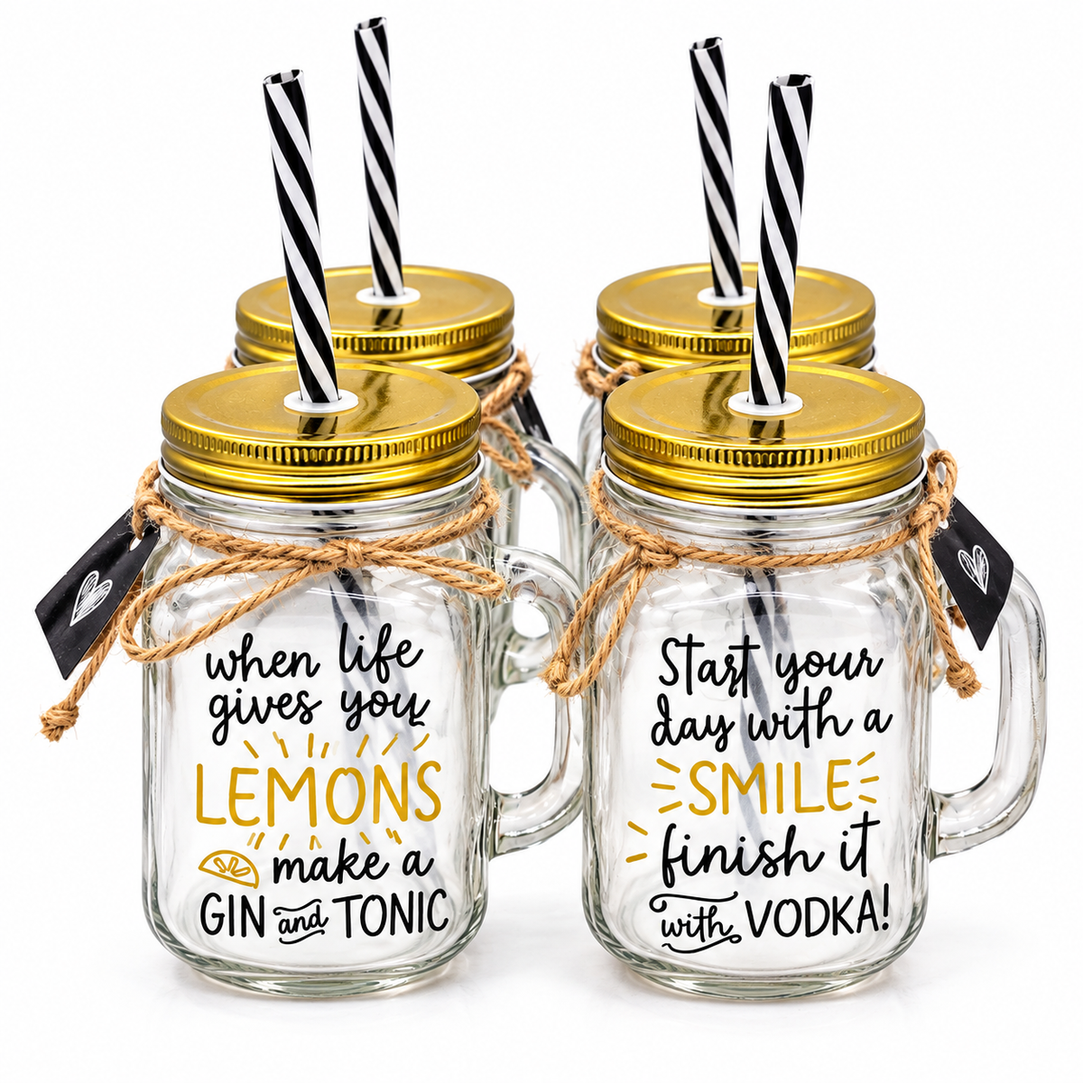 Four clear glass mason jar drinkware pieces with gold lids, black-and-white striped straws, and twine bows, arranged on a white background. The front jars have printed phrases in black and yellow text.