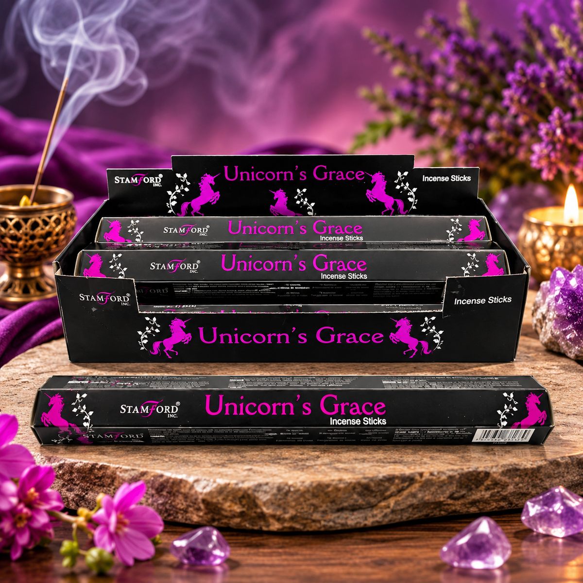Four boxes of Stamford Unicorn's Grace incense sticks arranged on a stone slab with purple fabric, flowers, crystals, and burning incense in the background.