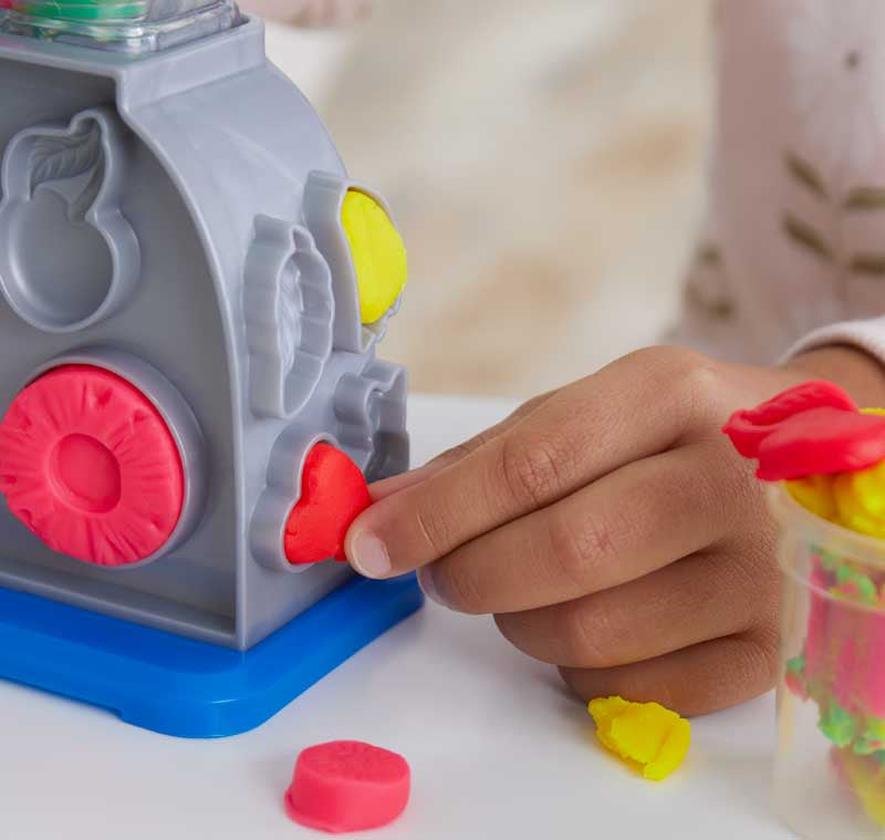 Child playing with a colourful Play-doh toy that has different shaped holes.