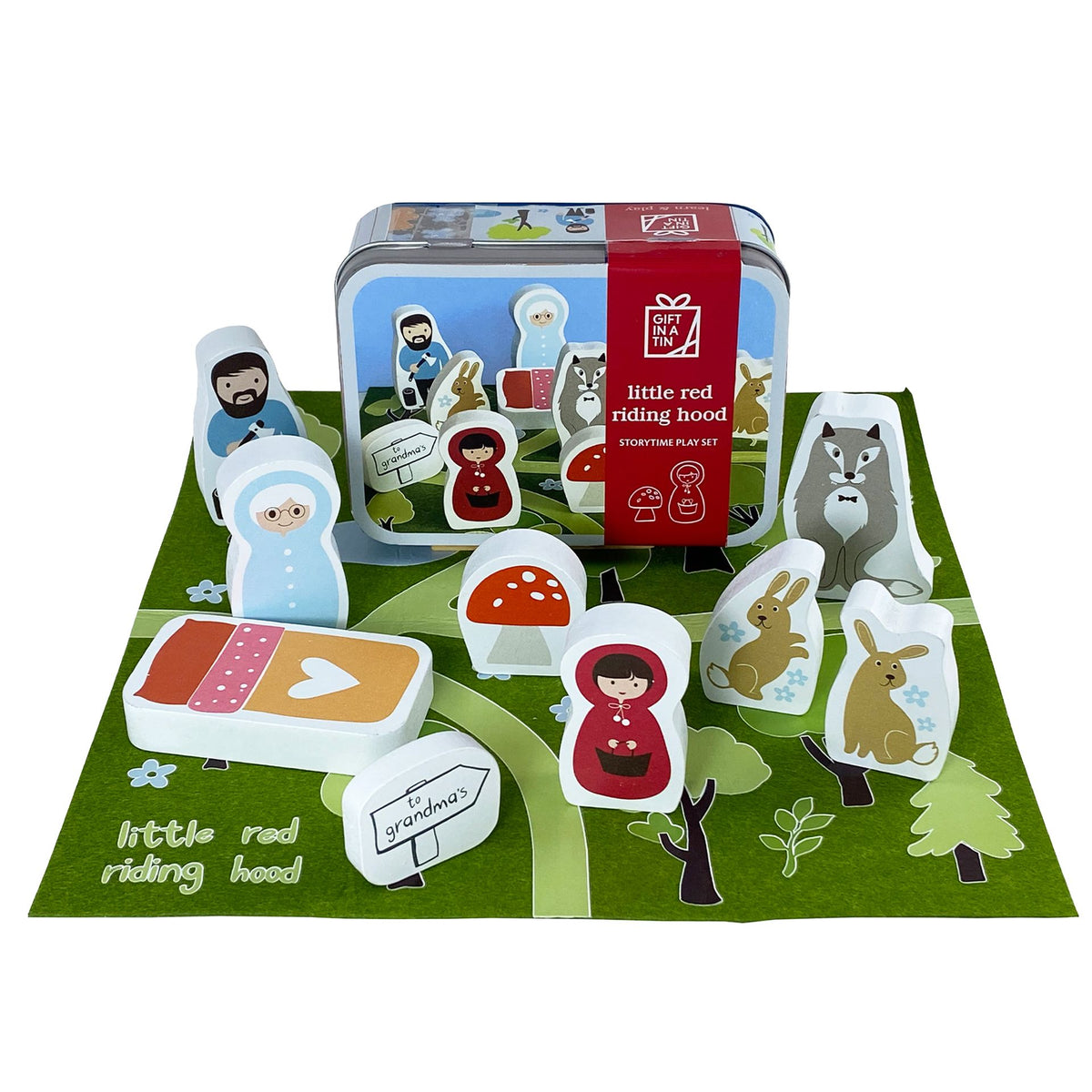 Storytime play set with characters and a tin labeled 'Little Red Riding Hood' on a green mat.