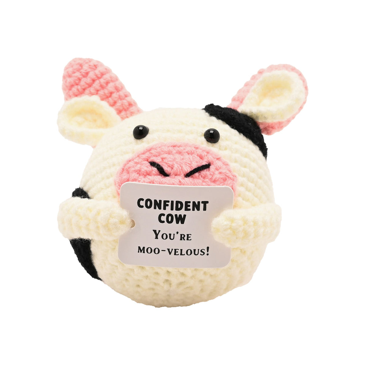 A crocheted cow plush toy with a cream body, pink and black patches, and a tag that reads 'CONFIDENT COW YOU'RE MOO-VELOUS!' on a plain white background.