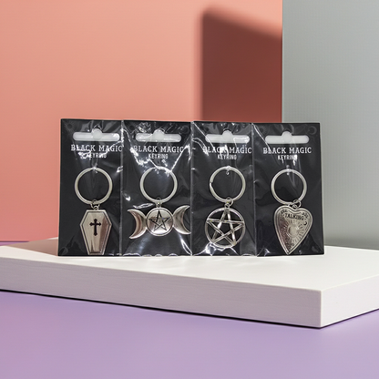 Four metal keychains with black Magic branding Keyrings available include a Coffin, Planchette, Pentagram & Pentagram with Moons