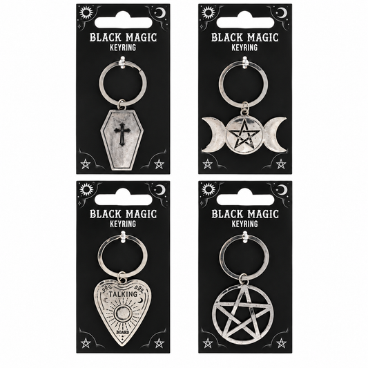 Four silver metal keyrings on black hanging cards labeled 'BLACK MAGIC KEYRING,' featuring coffin, triple moon, playing card, and pentagram designs.