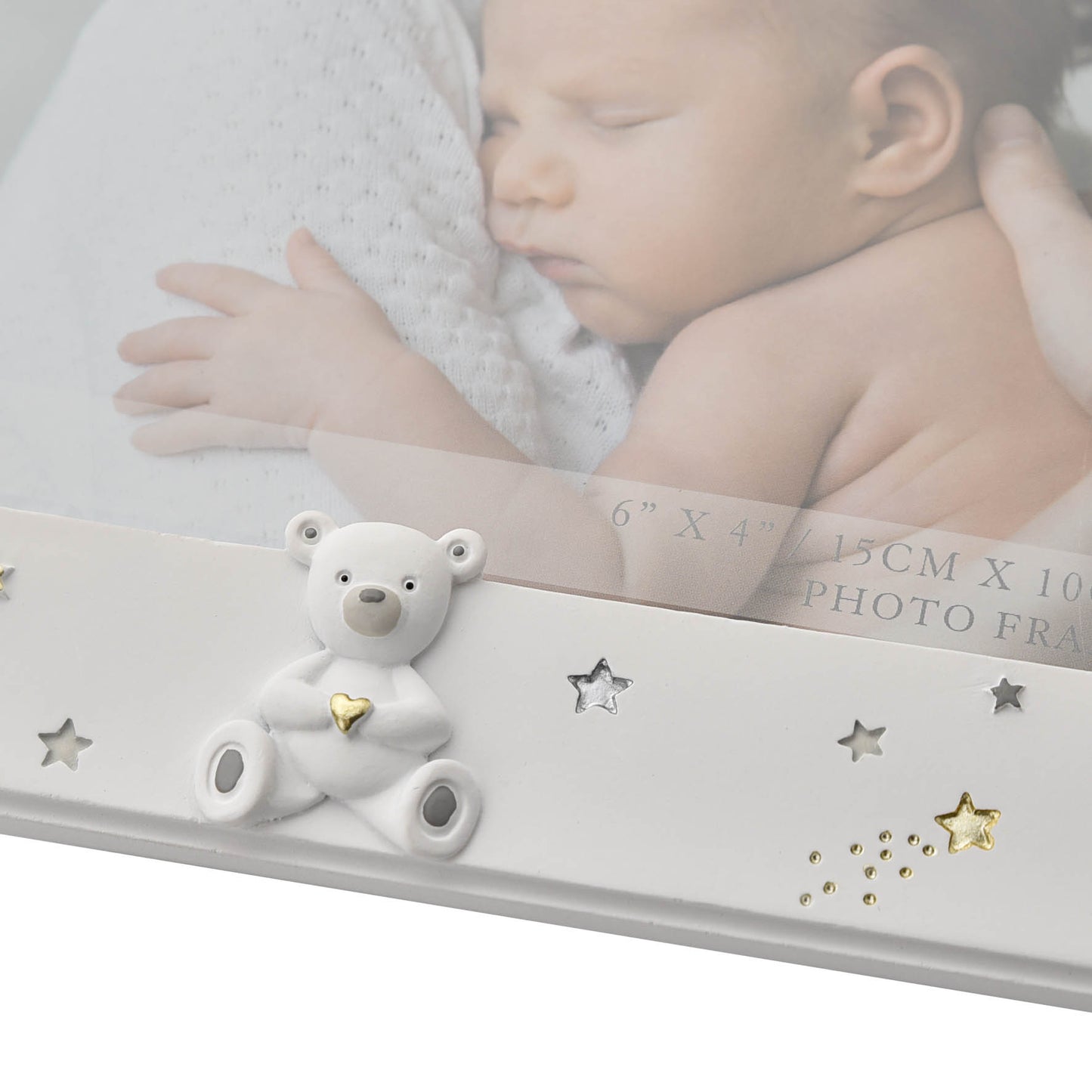White photo frame with a bear ornament and decorative stars on a blurred background of a baby.