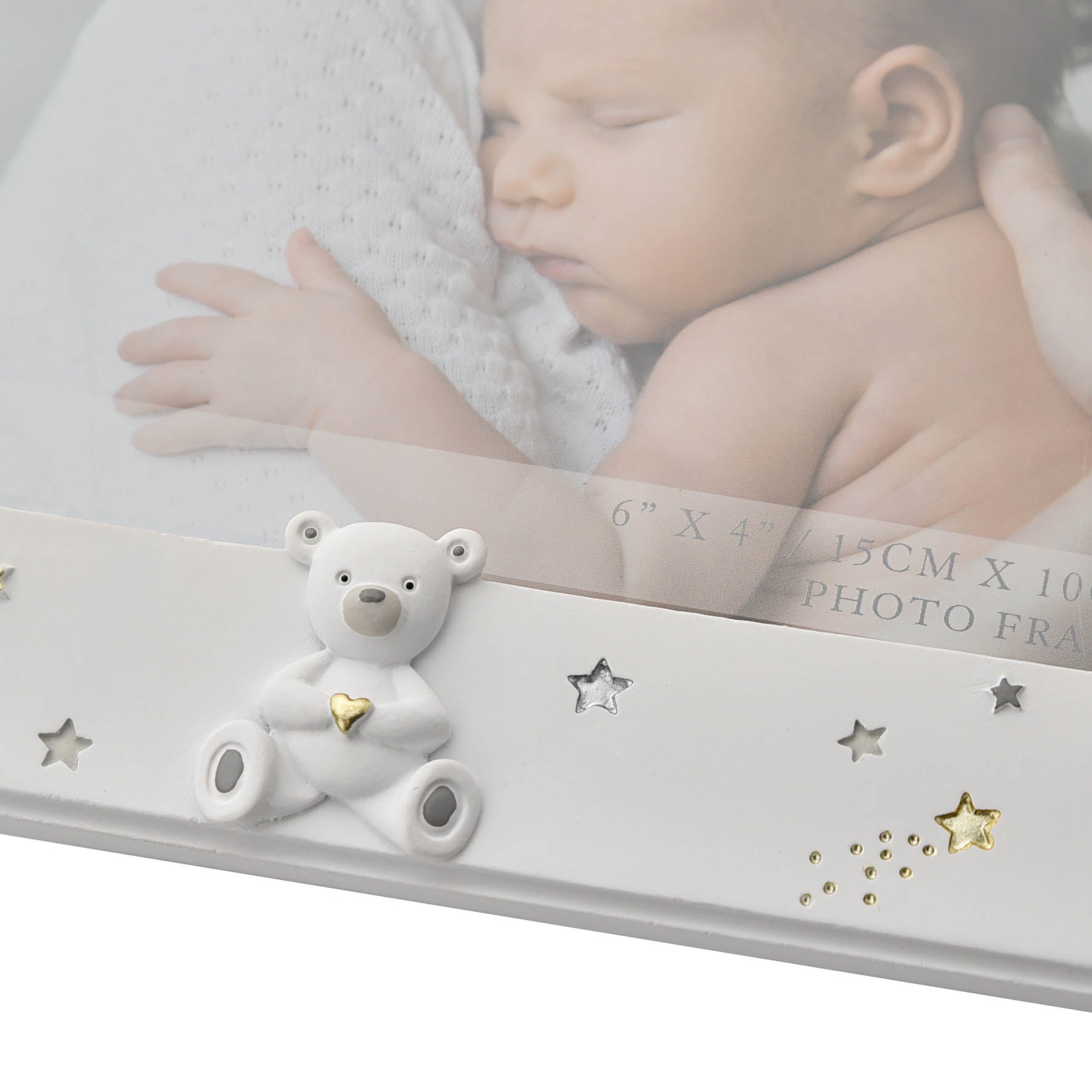 White photo frame with a bear ornament and decorative stars on a blurred background of a baby.