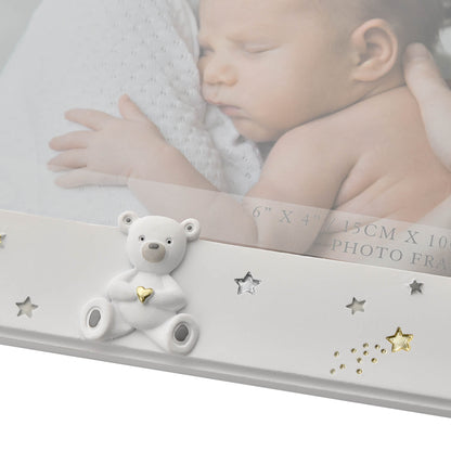 White photo frame with a bear ornament and decorative stars on a blurred background of a baby.