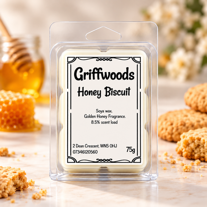 A packaged wax melt labeled 'Griffwoods Honey Biscuit' in a clear plastic clamshell package, centered on a light marble surface with blurred honeycomb, a honey dipper, and biscuit pieces around it.