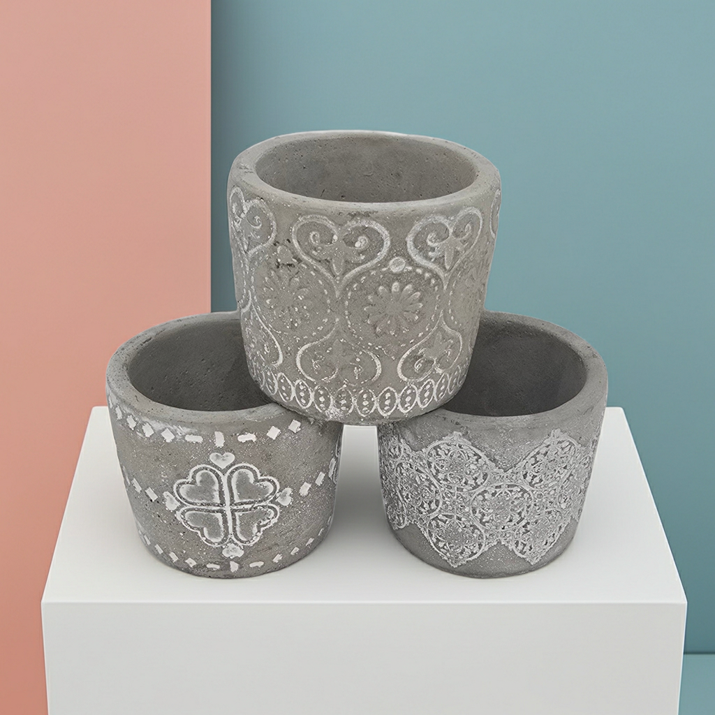 Three decorative concrete Candle Holders with intricate patterns on a white platform against a multicolored background.