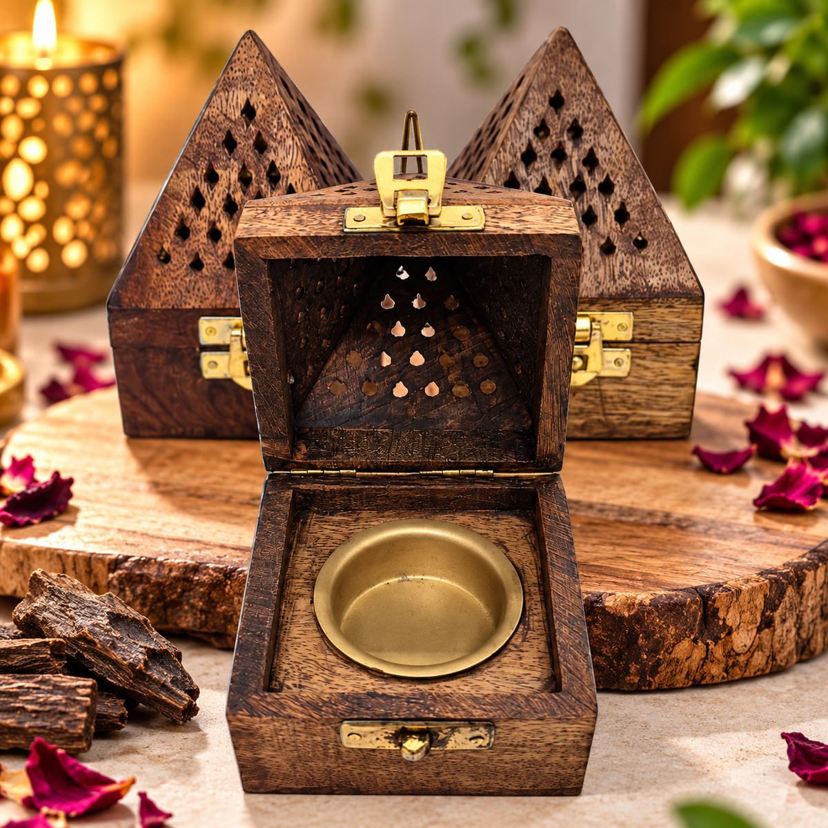 An open dark wood box with brass latches and a round brass bowl inside, styled on a wooden surface with dried petals and a candle in the background.