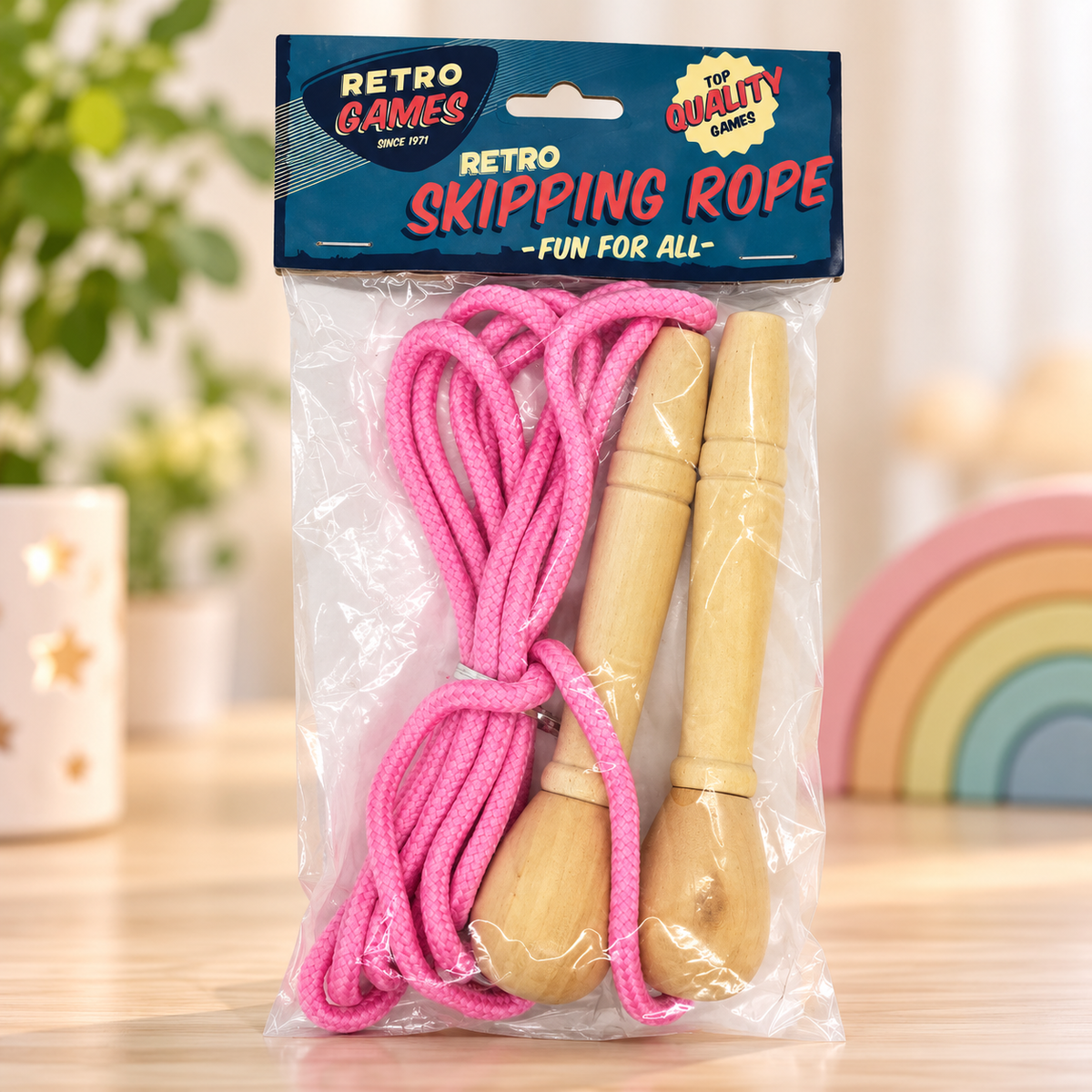 A packaged children's skipping rope set with bright pink rope and light natural wood handles, sealed in a clear plastic bag with a blue header card reading 'RETRO SKIPPING ROPE' and 'Retro Games'.