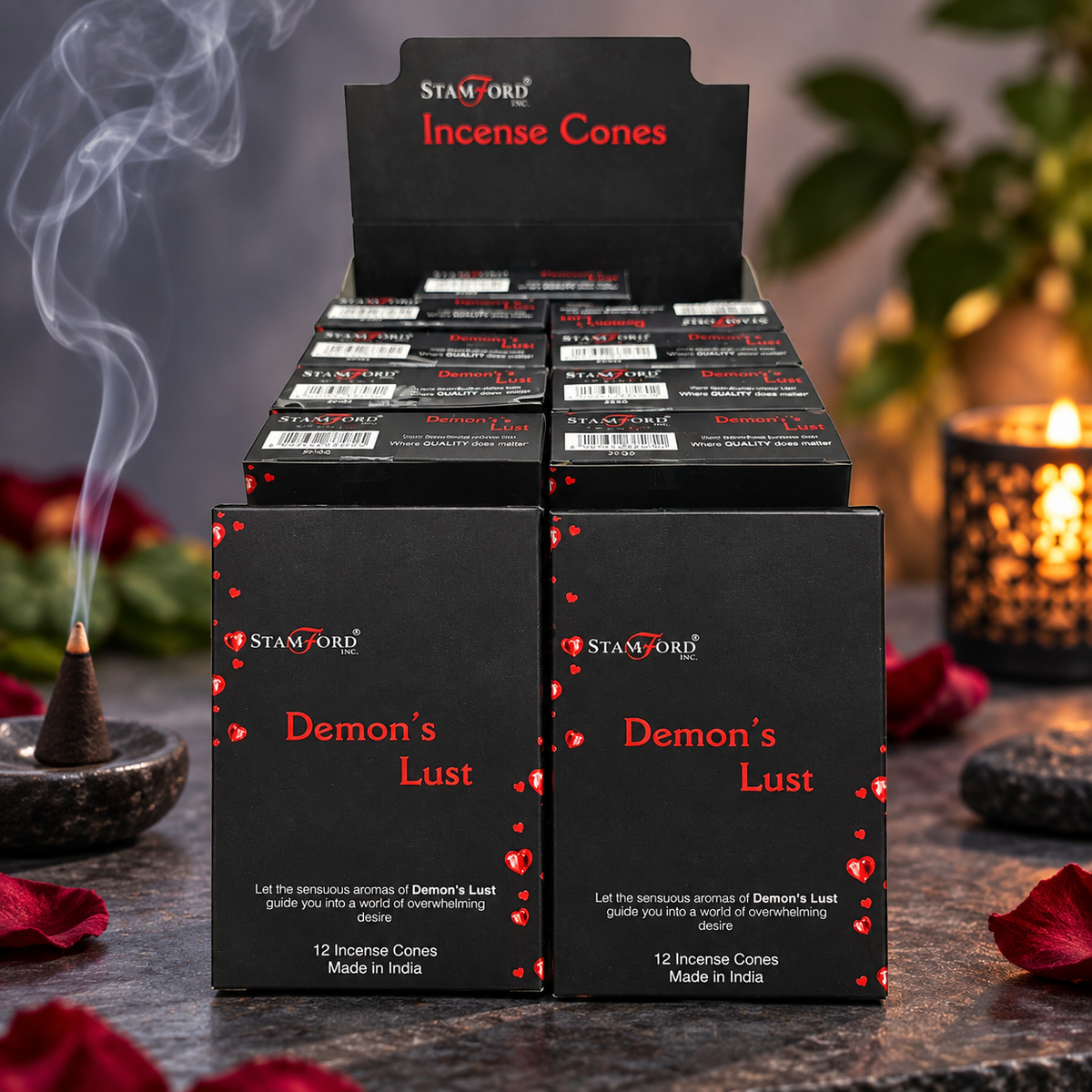 A retail display box and individual packs of Stamford Demon's Lust Incense Cones, styled with a smoking incense cone, a lit candle, and scattered rose petals on a dark stone surface.