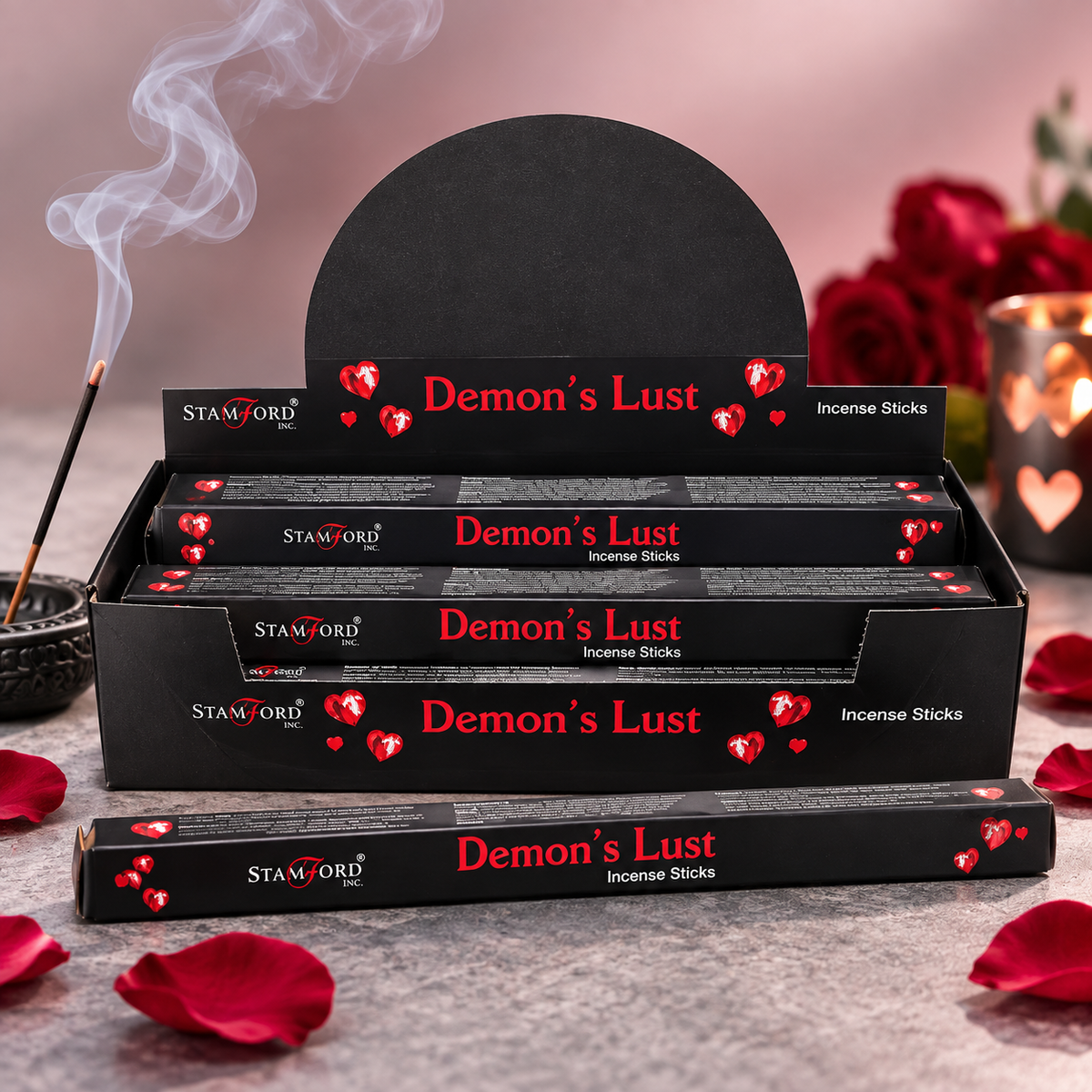 Several black boxes of Stanford Incense Sticks labeled 'Demon's Lust' are arranged on a stone surface with rose petals, a smoking incense stick in a holder, and blurred red roses and a heart-lit candle in the background.