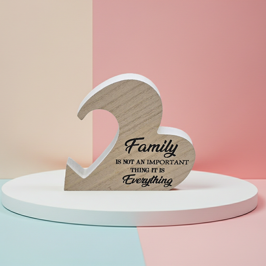 Wooden heart-shaped sign with 'Family is not an important thing, it is everything' text on a pastel background