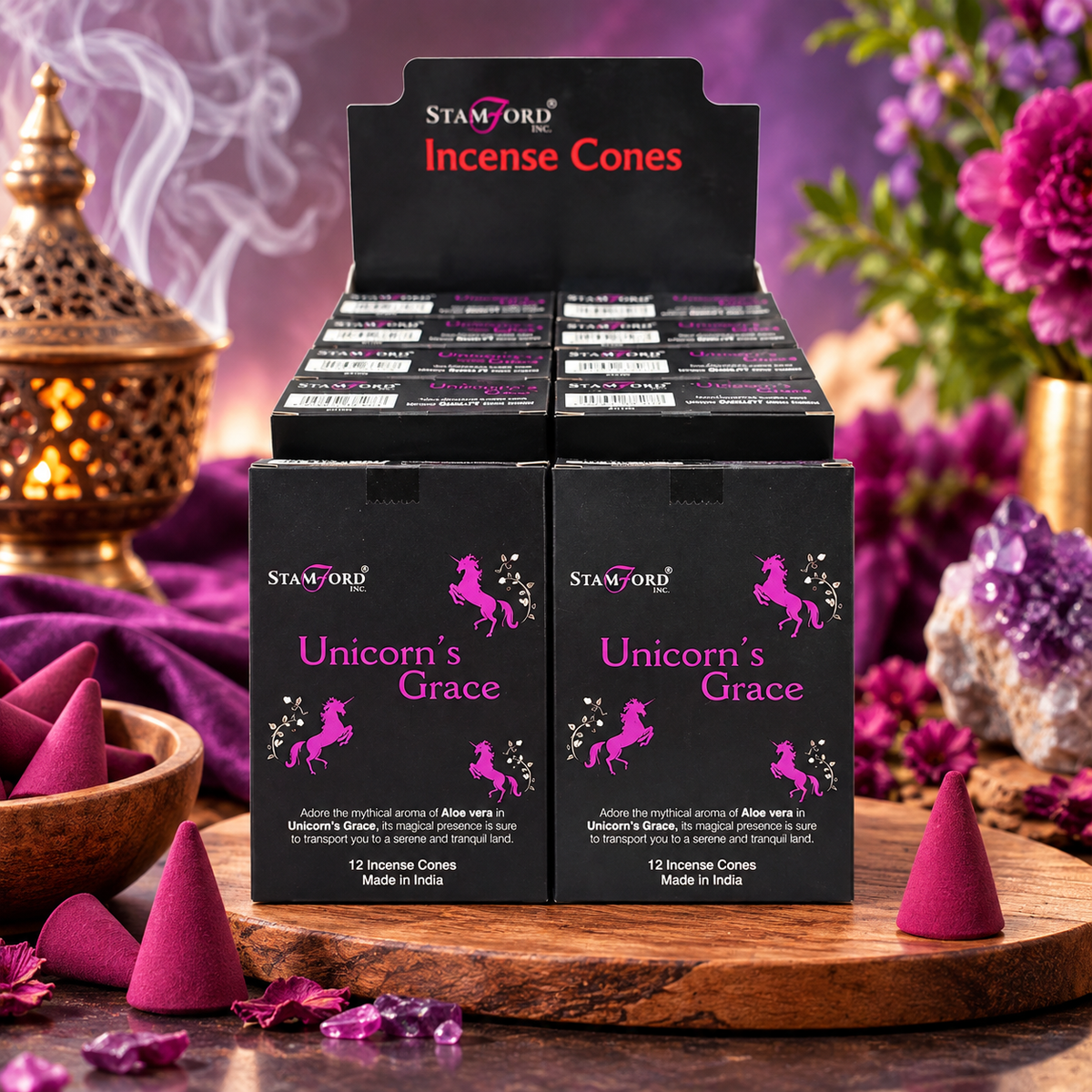 Two black boxes of Stamford Incense Cones labeled 'Unicorn's Grace' displayed on a wooden stand, with additional pink incense cones and purple floral decor in the background.
