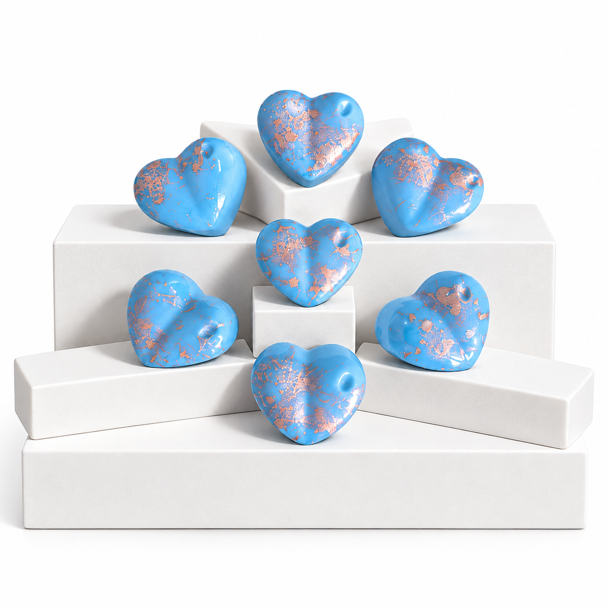 Seven glossy light blue heart-shaped Wax Melts, arranged on white display blocks against a white background.