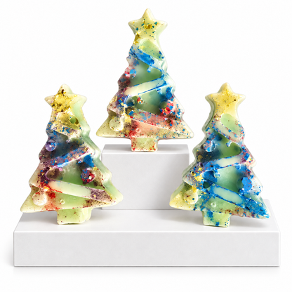 Three small Christmas tree-shaped Wax Melts with star tops, displayed on white risers against a white background. The ornaments have a pale green base with swirling blue, yellow, red, and purple glitter-like patterns.