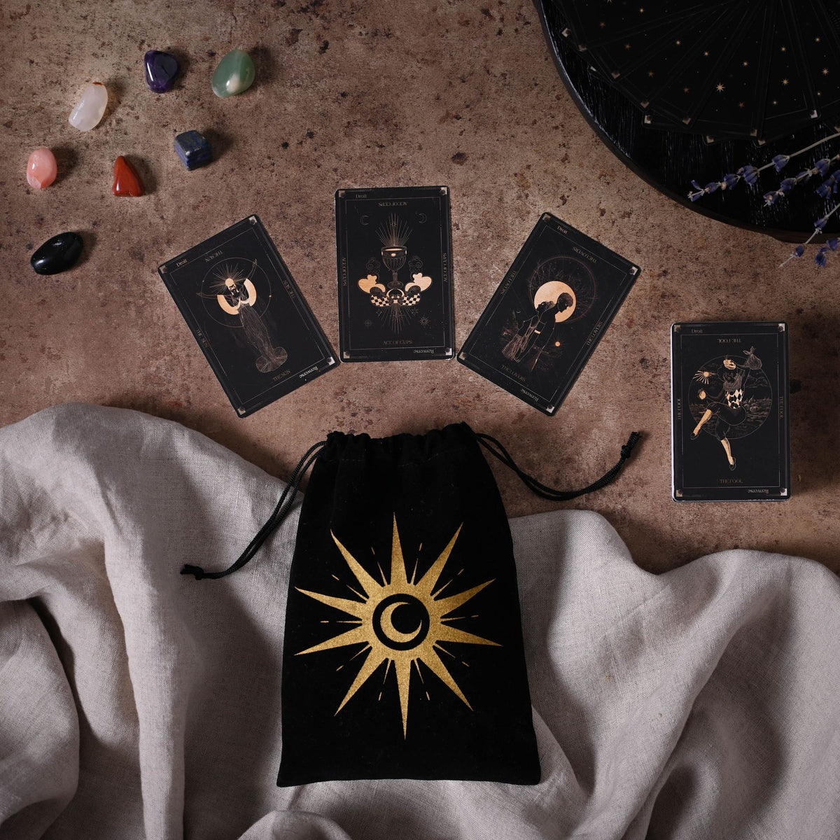 Set of tarot cards with a drawstring bag featuring a star design on a textured surface.