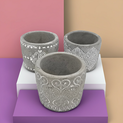 Three decorative concrete Candle Holders with intricate patterns on a white platform against a multicolored background.